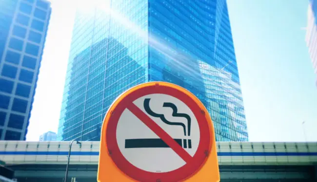 A no smoking sign on display outside city centre skyscrappers